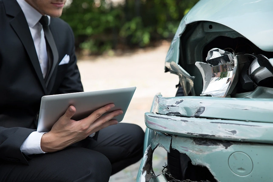 Suited person with checklist looking at car headlight